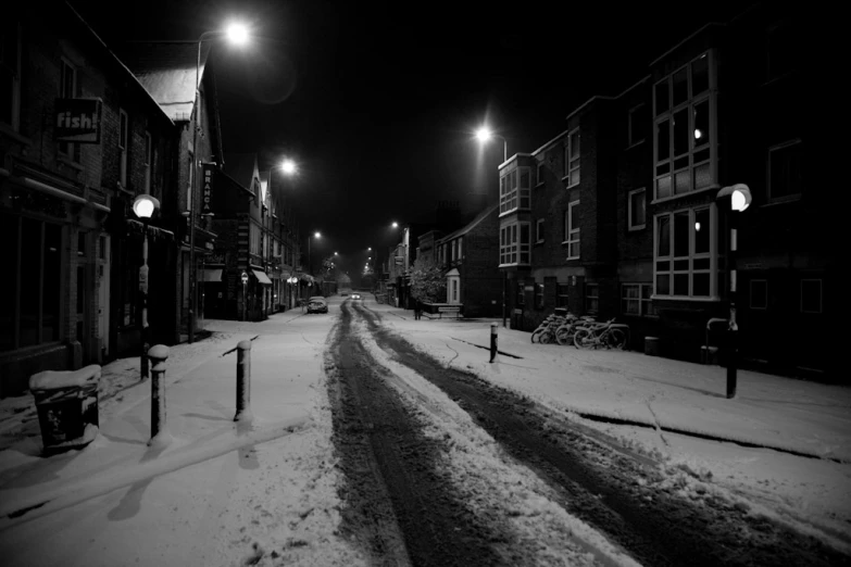 a street covered in snow at night with street lamps