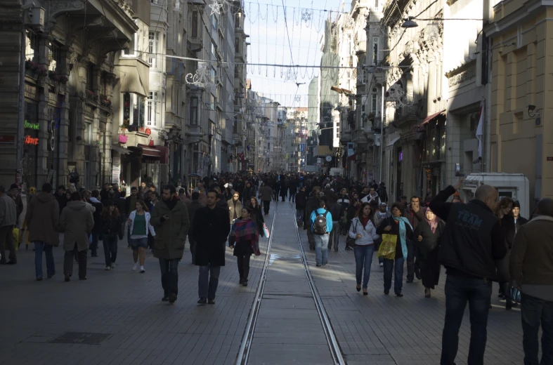 a large crowd is walking down a narrow street