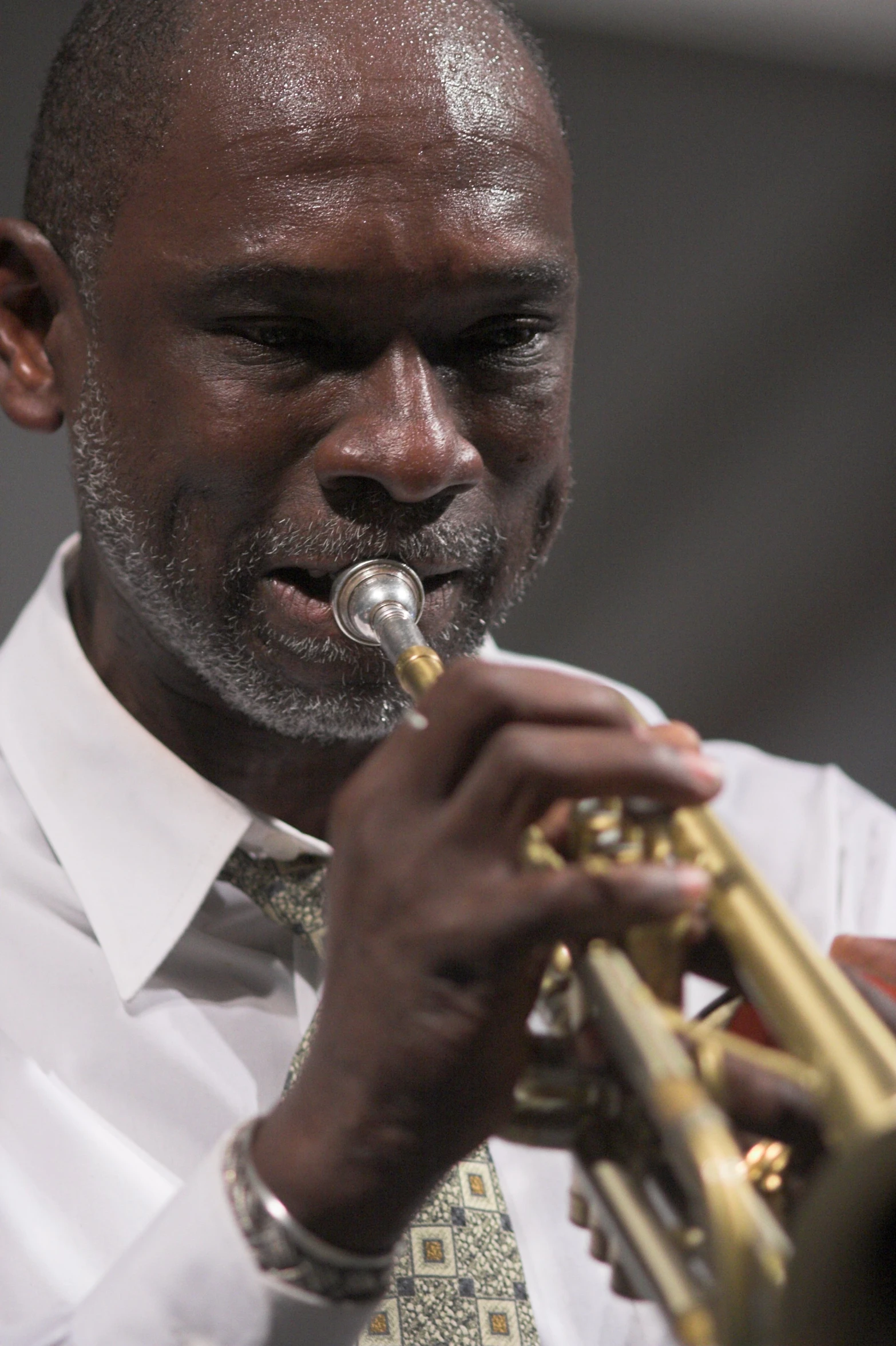 a man in a white shirt and tie playing a trumpet