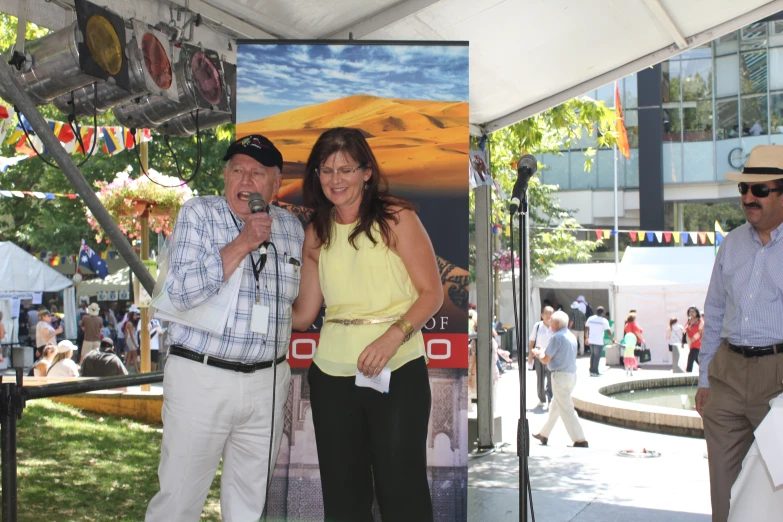 the man and woman are standing in front of a microphone