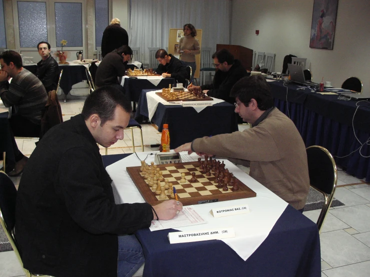 a couple of men playing chess in front of people