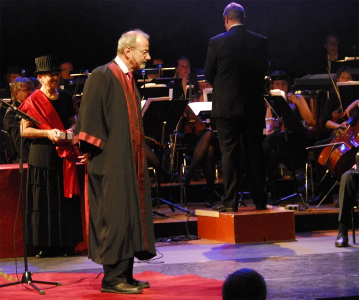 a conductor standing next to a choir singing at an event