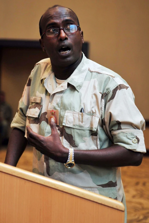 a man in army fatigues speaks from a podium