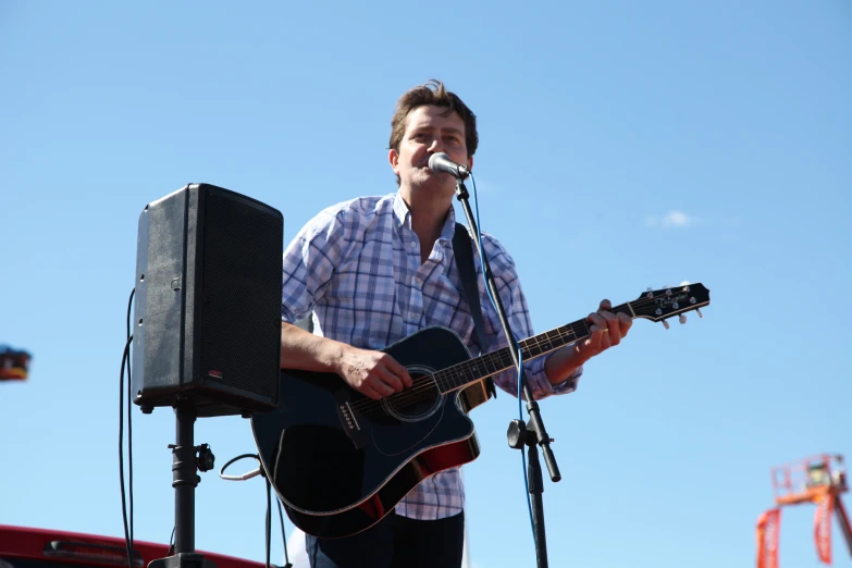 the man is singing into his guitar and playing the keyboard