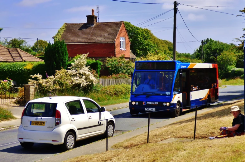 a blue bus is stopped as a white van waits on the side