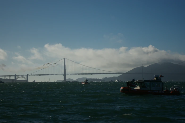 boats ride in the open water next to a bridge