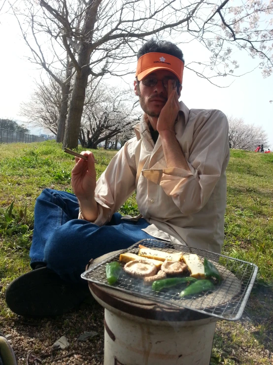 a man sitting down with food in the grass