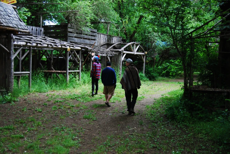 four people walking down a path in a forest