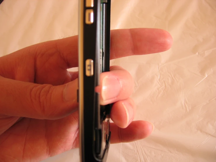 a hand holding a small device on top of a table