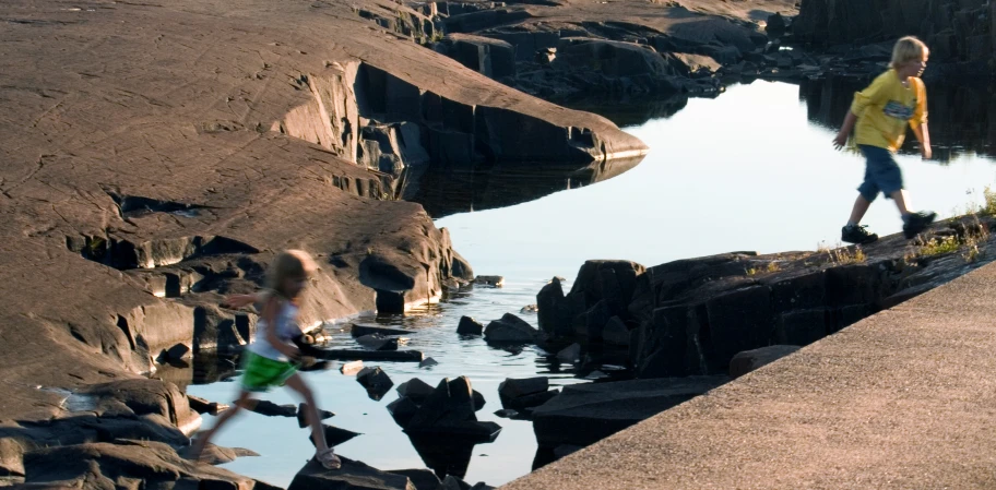 the little boys are running near some water