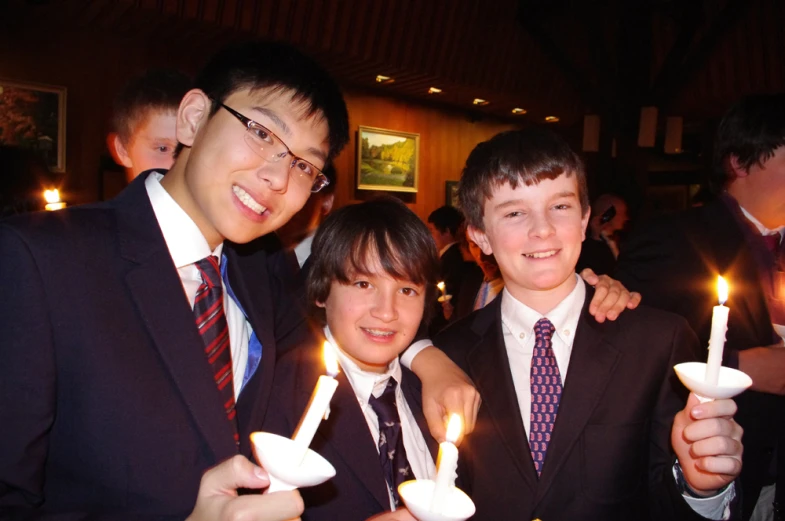 three people standing together while holding candles