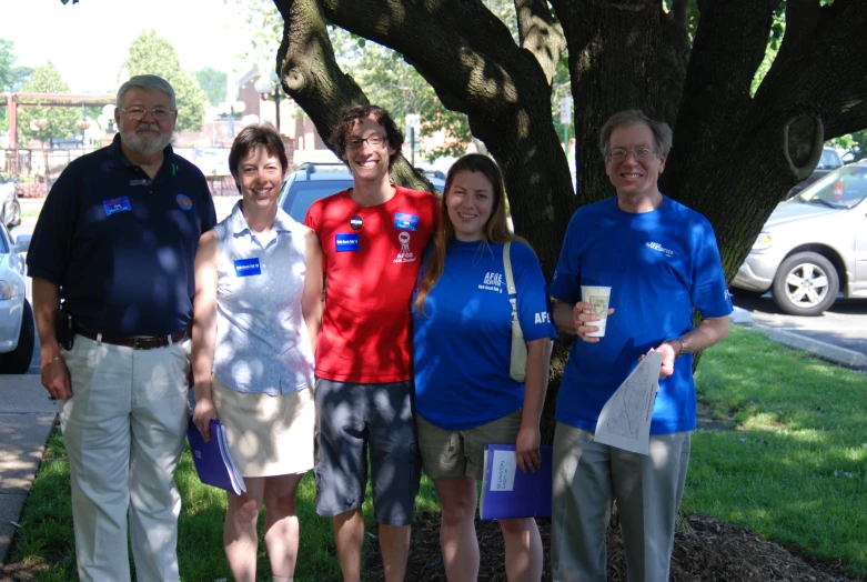 several people standing underneath a tree on a grass field