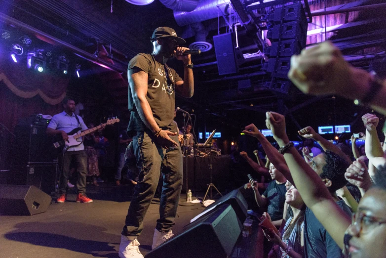 a man in black standing on top of a stage with fans