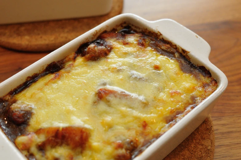 a casserole in a white dish with cheese and mushrooms