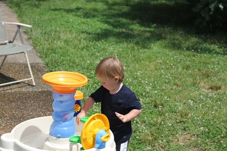 a little boy playing with a water table