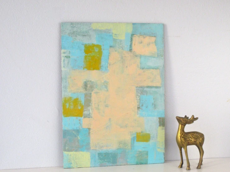 a small ss deer sculpture sitting in front of a painting