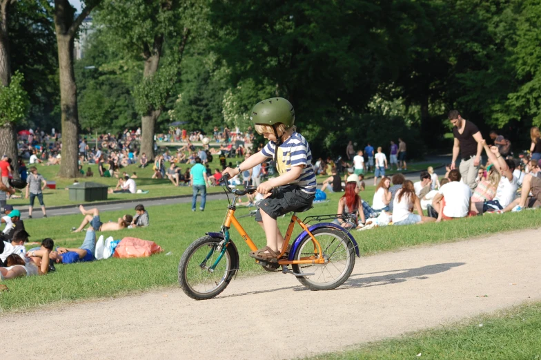 a young man rides his bicycle in front of a large group of people