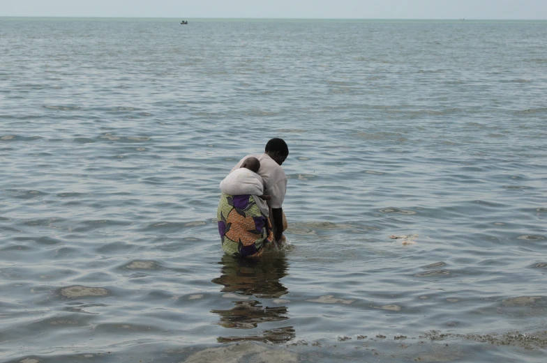 two people standing in the ocean looking at soing