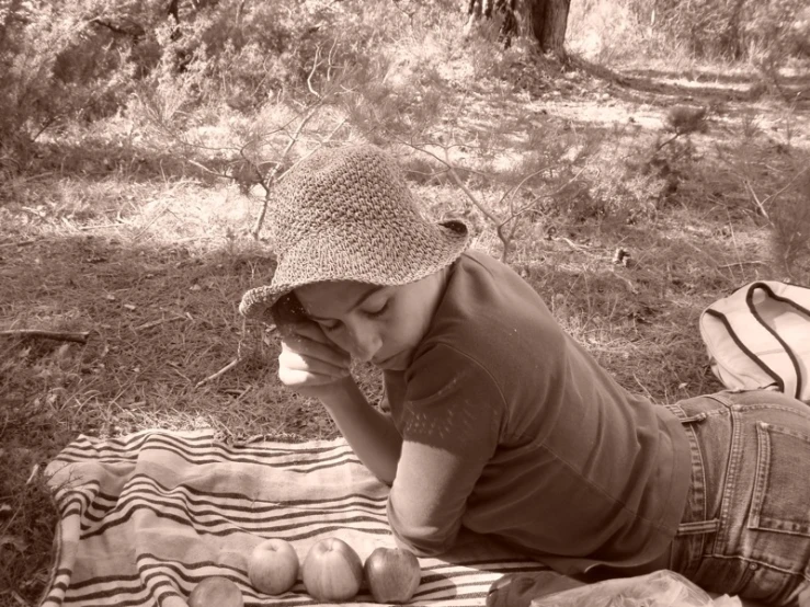 a black and white image of a woman sitting on a blanket holding a bottle