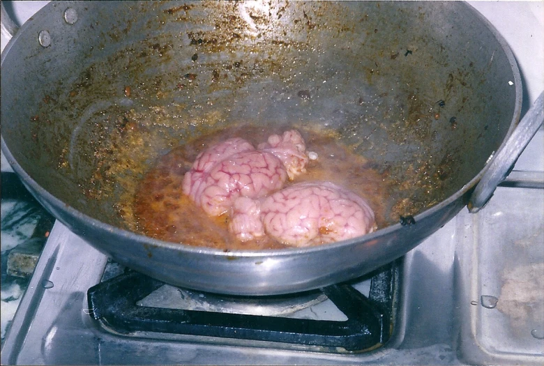 two meatballs are cooking in a large frying pan