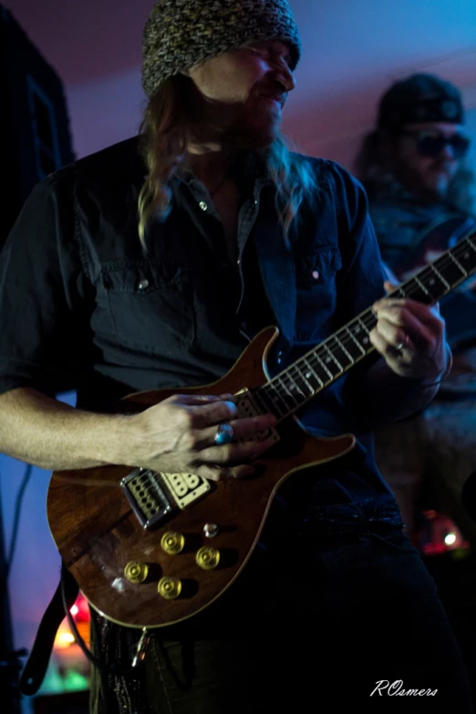 a guy holding an electric guitar and wearing a hat