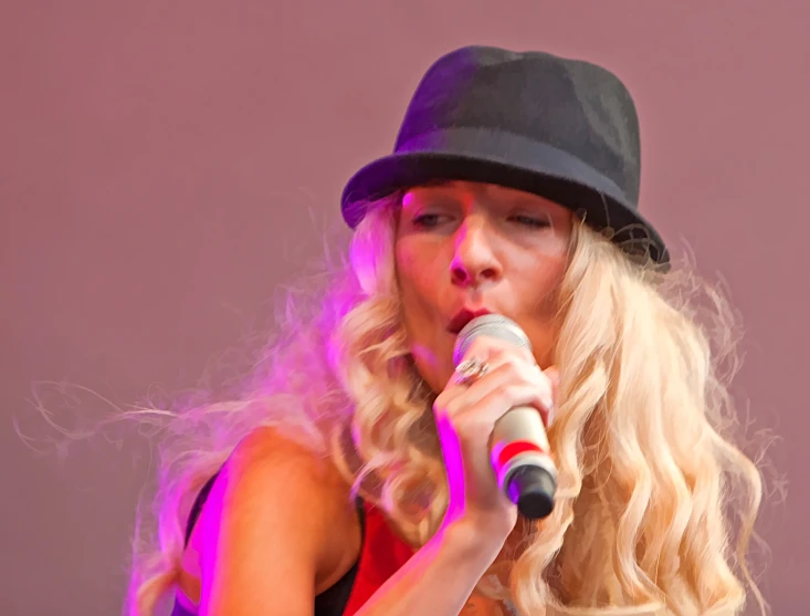 a blonde haired woman with a black hat singing