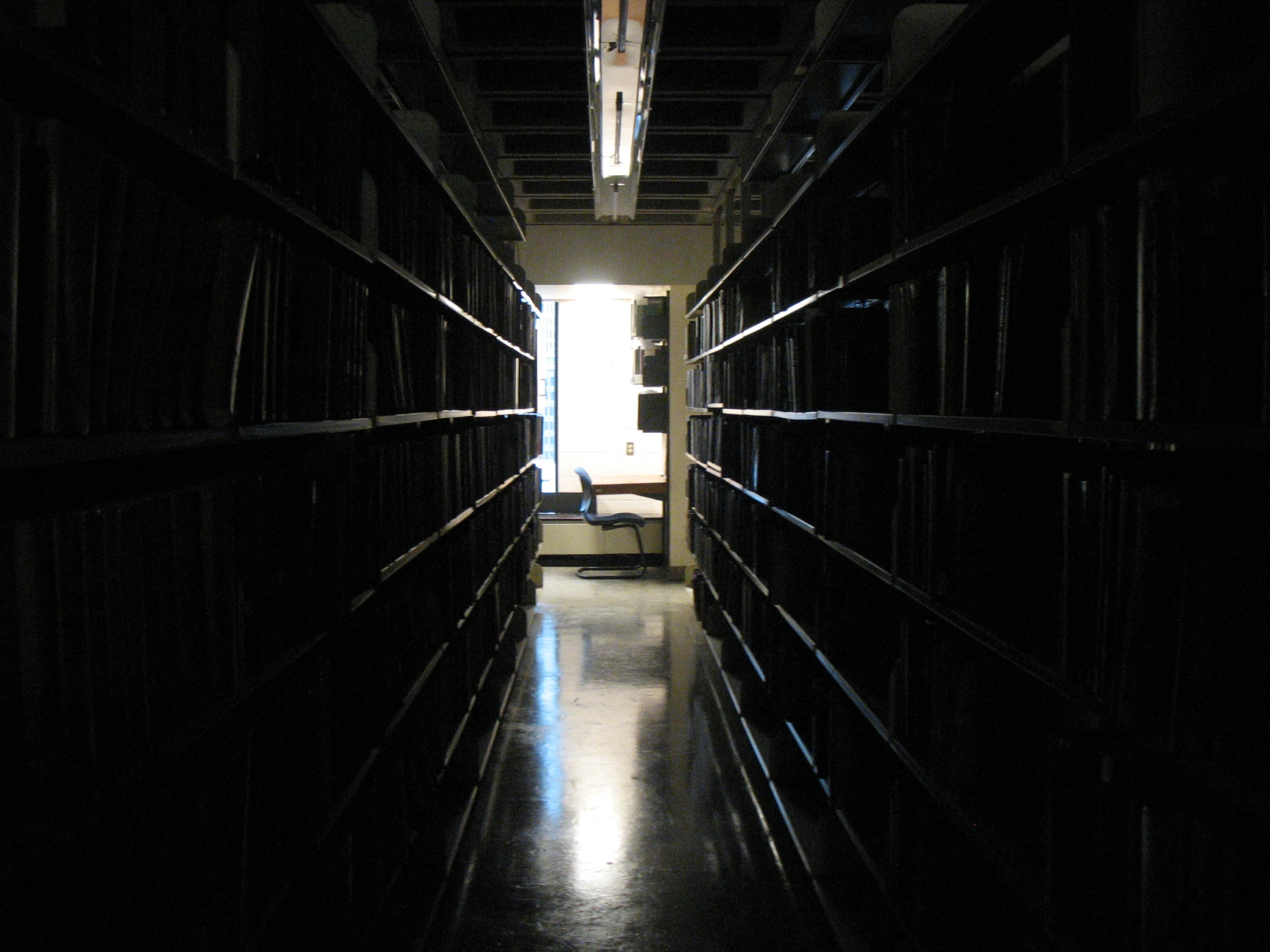 a long dark hallway with lots of shelves on the wall