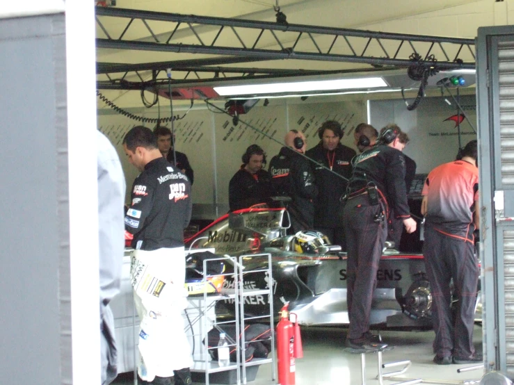 a group of people are around a car in the garage