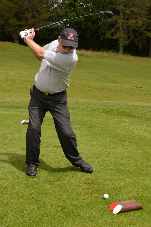 a man on the grass swings at a tee