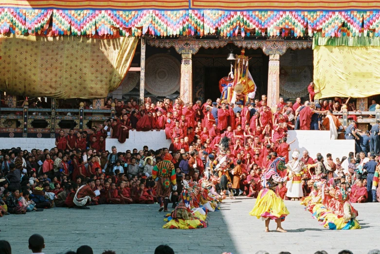 a large crowd watching two men performing in traditional indian attire