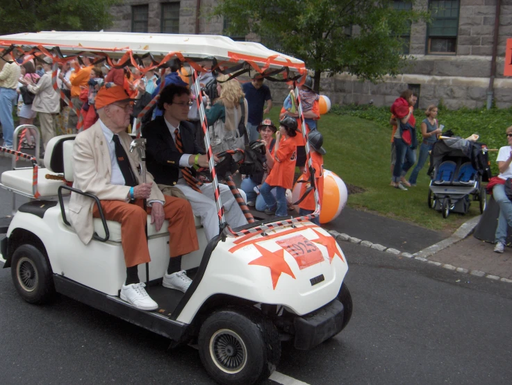 an older couple rides in an orange and white cart with their child on it