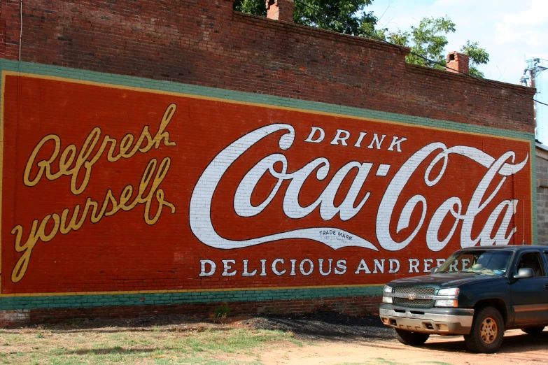 the large coca - cola sign on the side of a building in a neighborhood