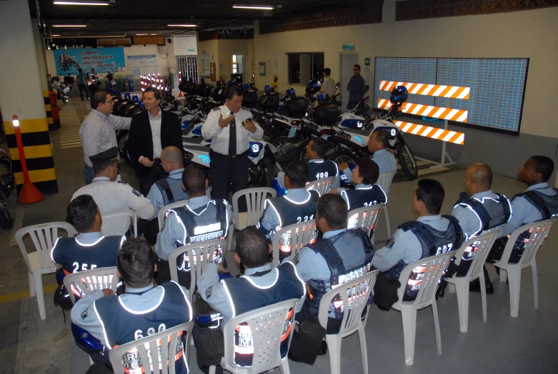 motorcycle cops sitting in chairs watching a man speak to them