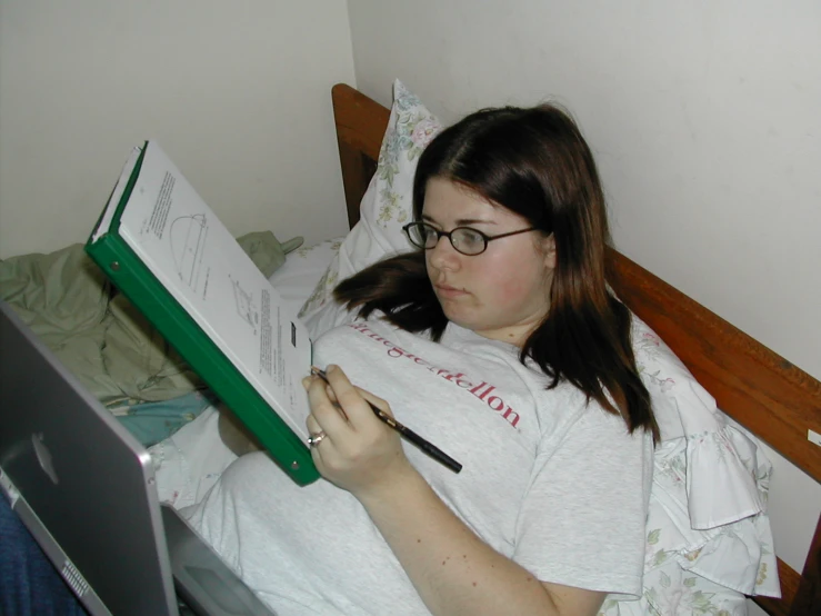 a girl reading a book and writing in a bed