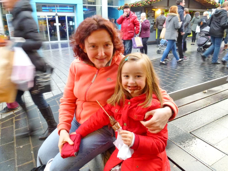 a woman and girl sitting together on a bench