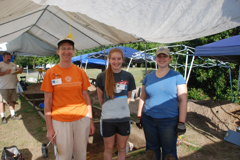 three people standing under tents in a field