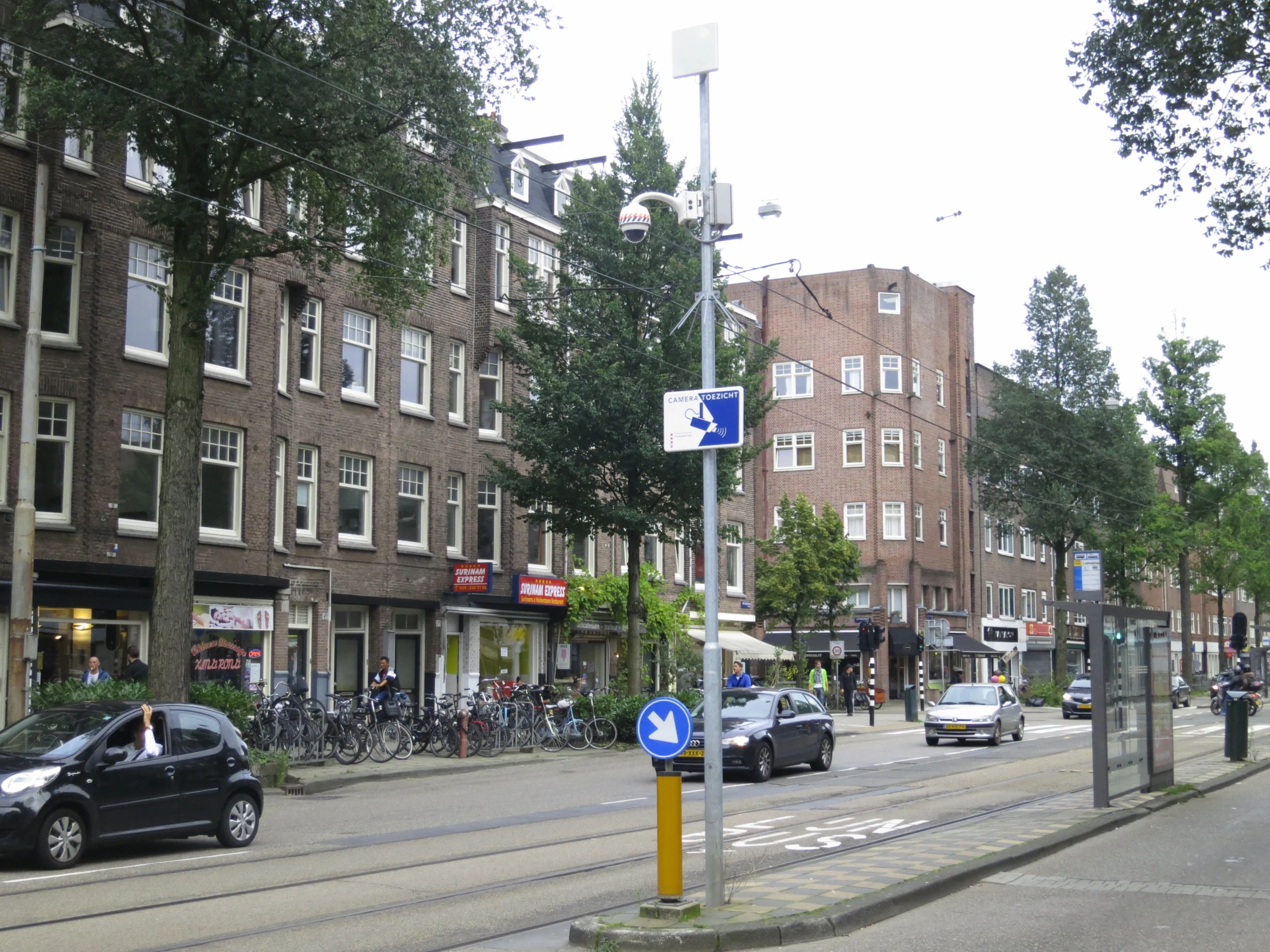 cars driving down a city street surrounded by tall buildings