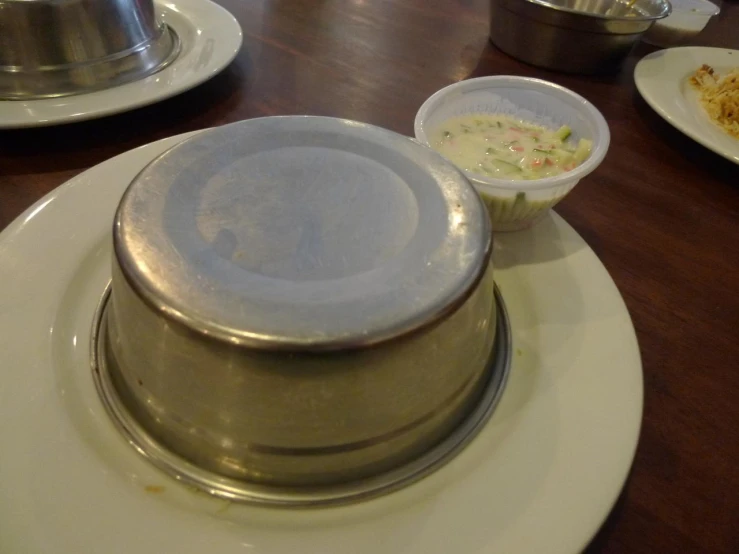 plates with silver and white dishes are set on a wooden table