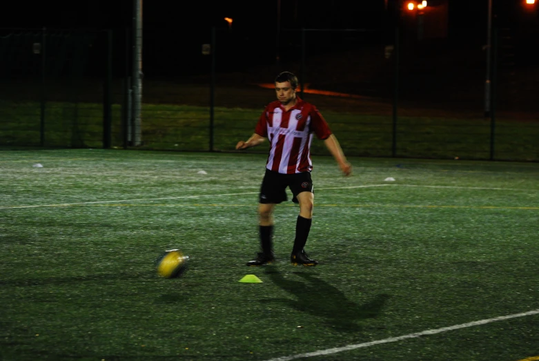 a man in red and white shirt kicking a soccer ball