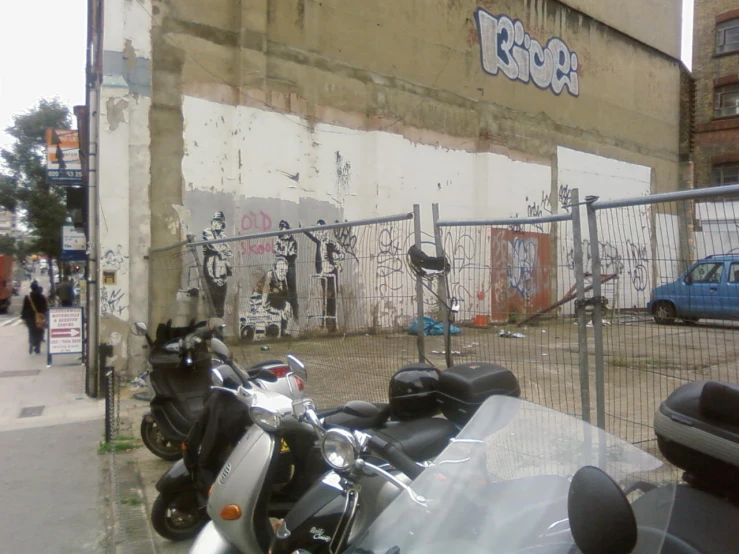 a row of parked mopeds sit in front of a building