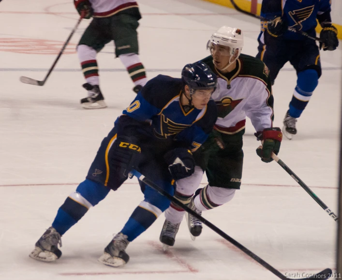 two hockey players playing on ice, one is holding the puck