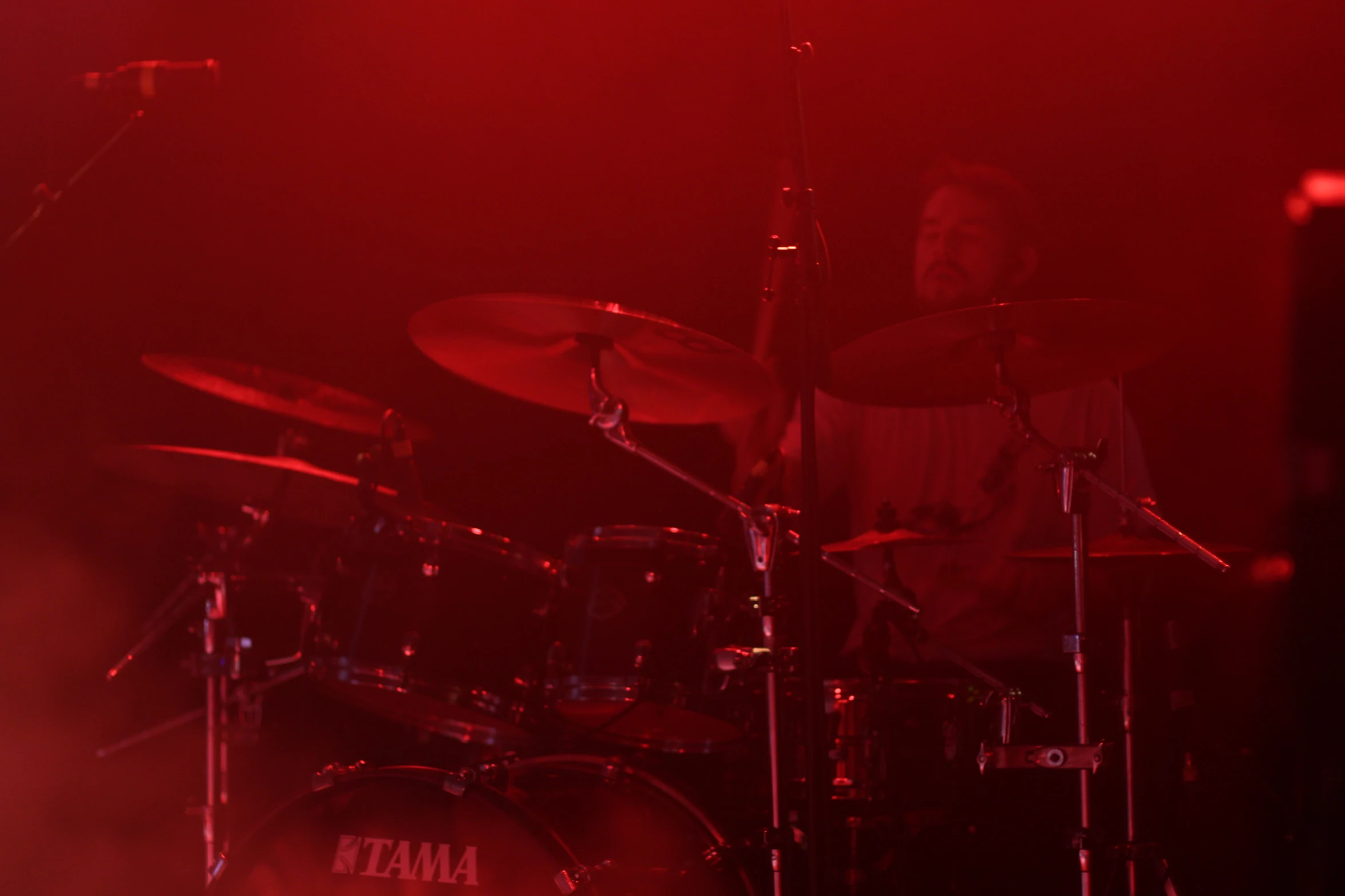 a drummer in a spotlight with a red light behind him