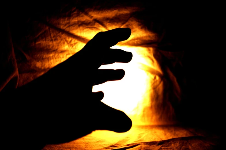 a person's hand pointing toward a glowing light