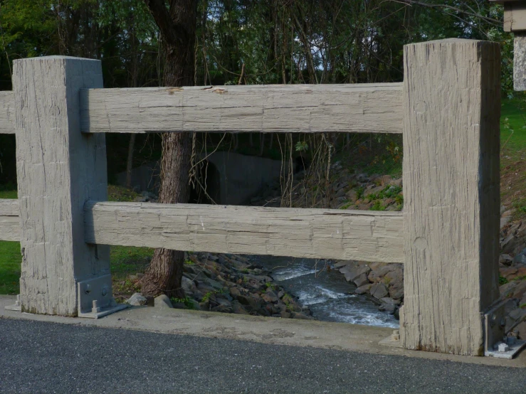 a wooden fence with a creek running by it