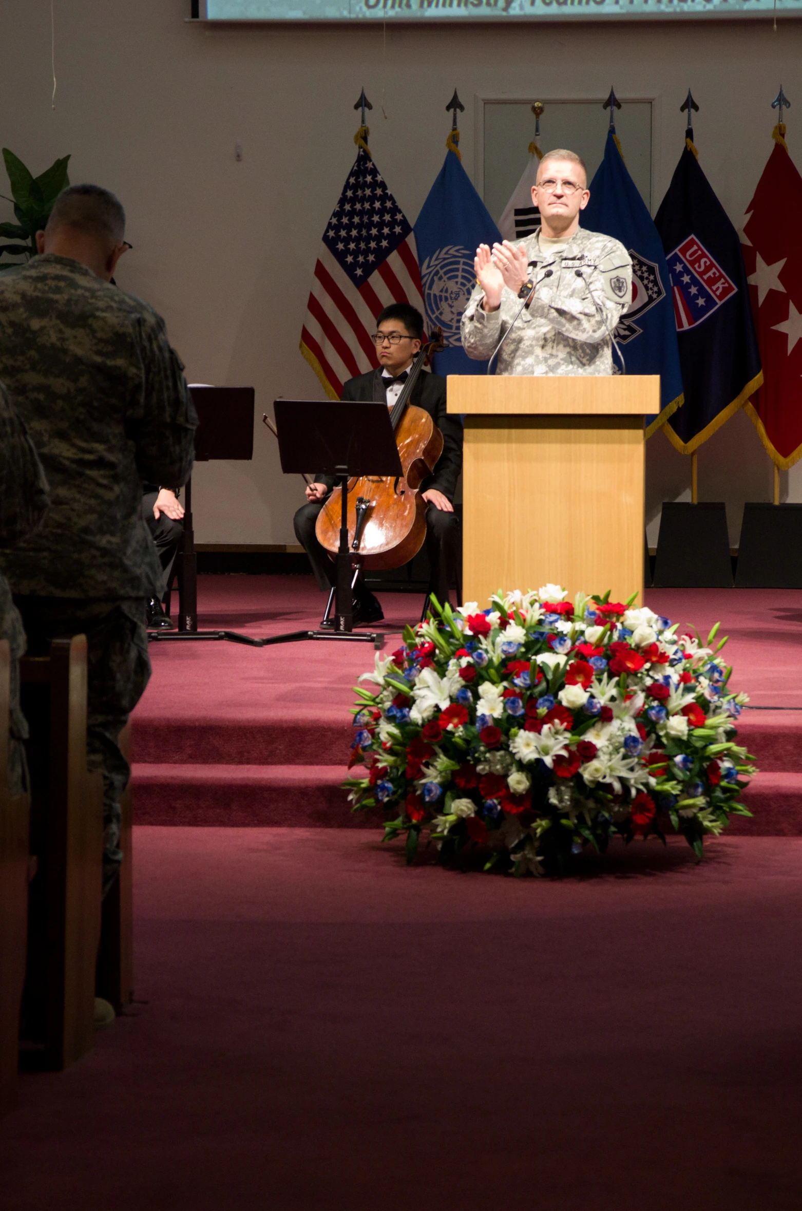 military personnel on stage giving speech to audience