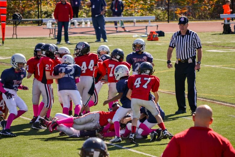 two teams of football players kneeling on the field while coaches and their opponents talk