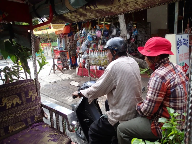 the two people are riding their scooter on the street