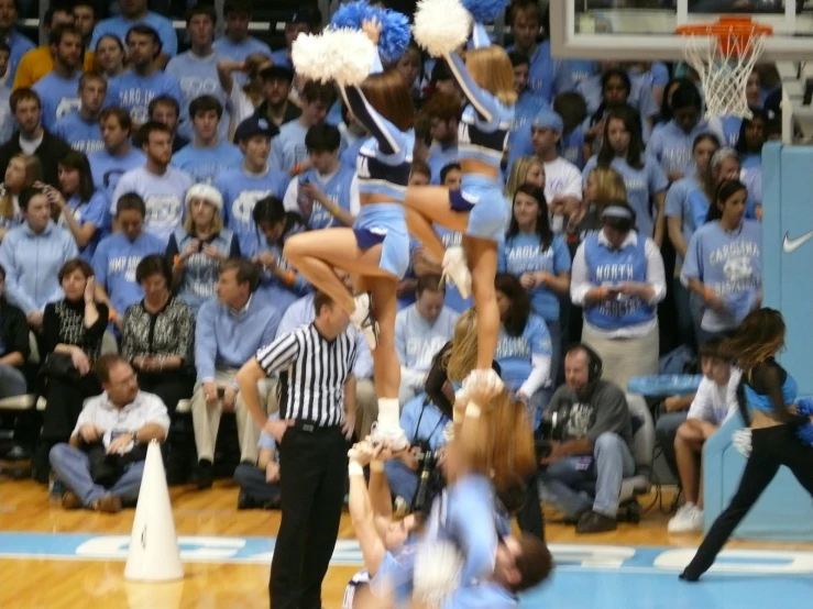 a cheerleader is doing tricks on a basketball court