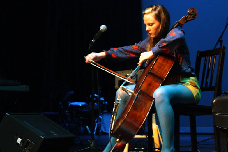 a woman sits in a chair while playing a cello