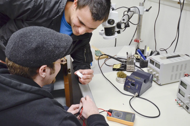 two men examining some electronic devices in a lab